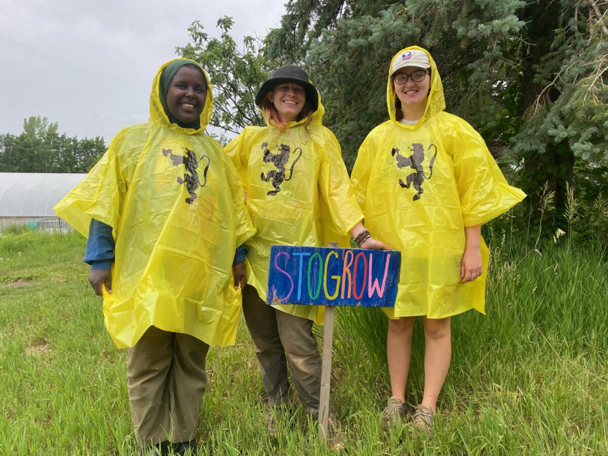 Three young women stand together wearing yellow rain ponchos.