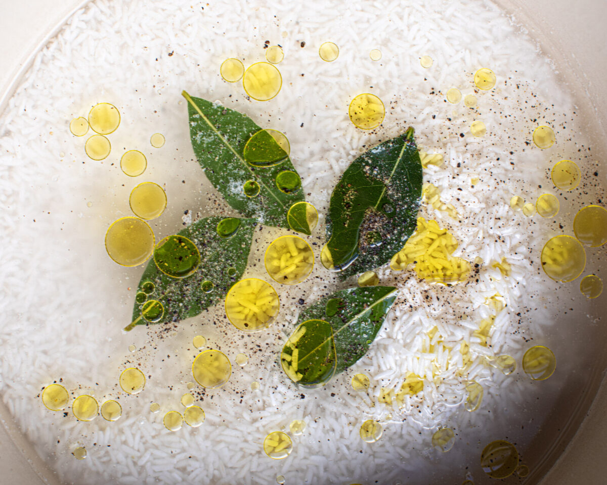 A pot of rice with bay leaves and oil.