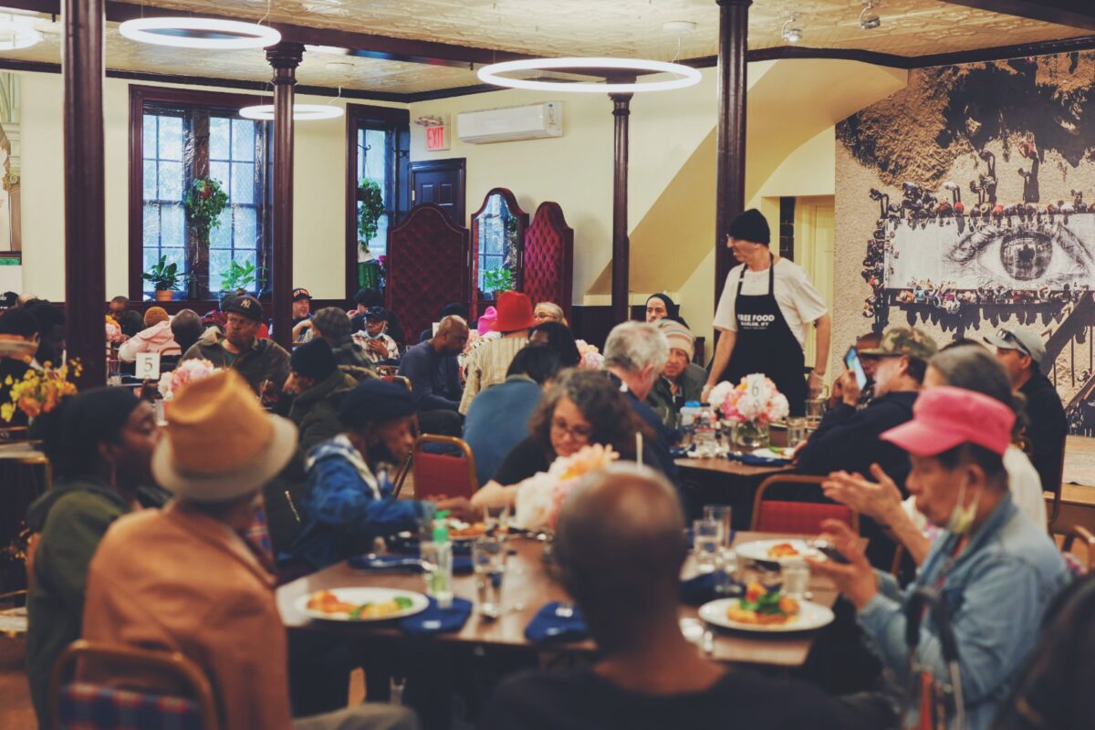 A group of people gather in a large dining room to share a meal together. 